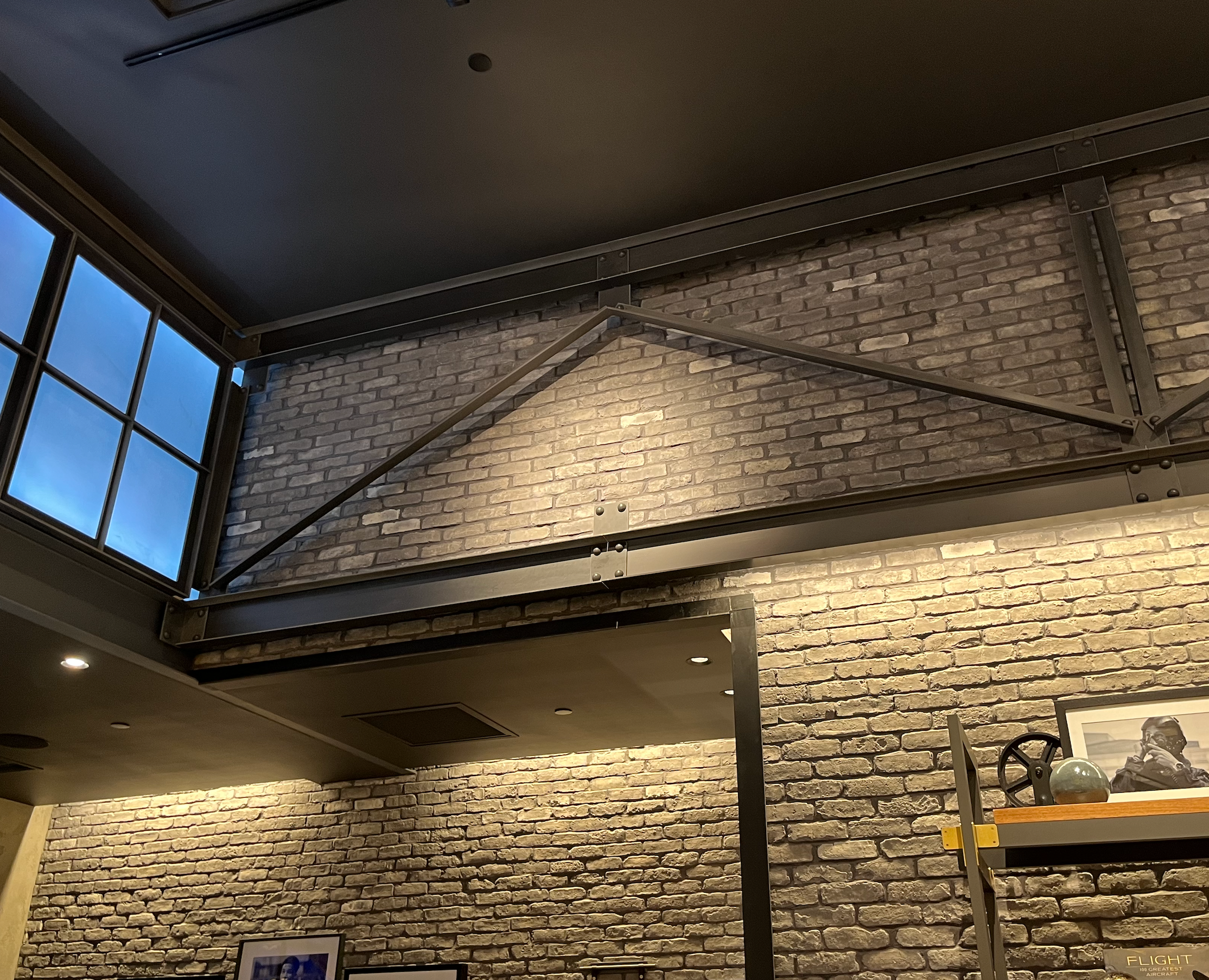 Faux windows and industrial trusses against exposed brick wall