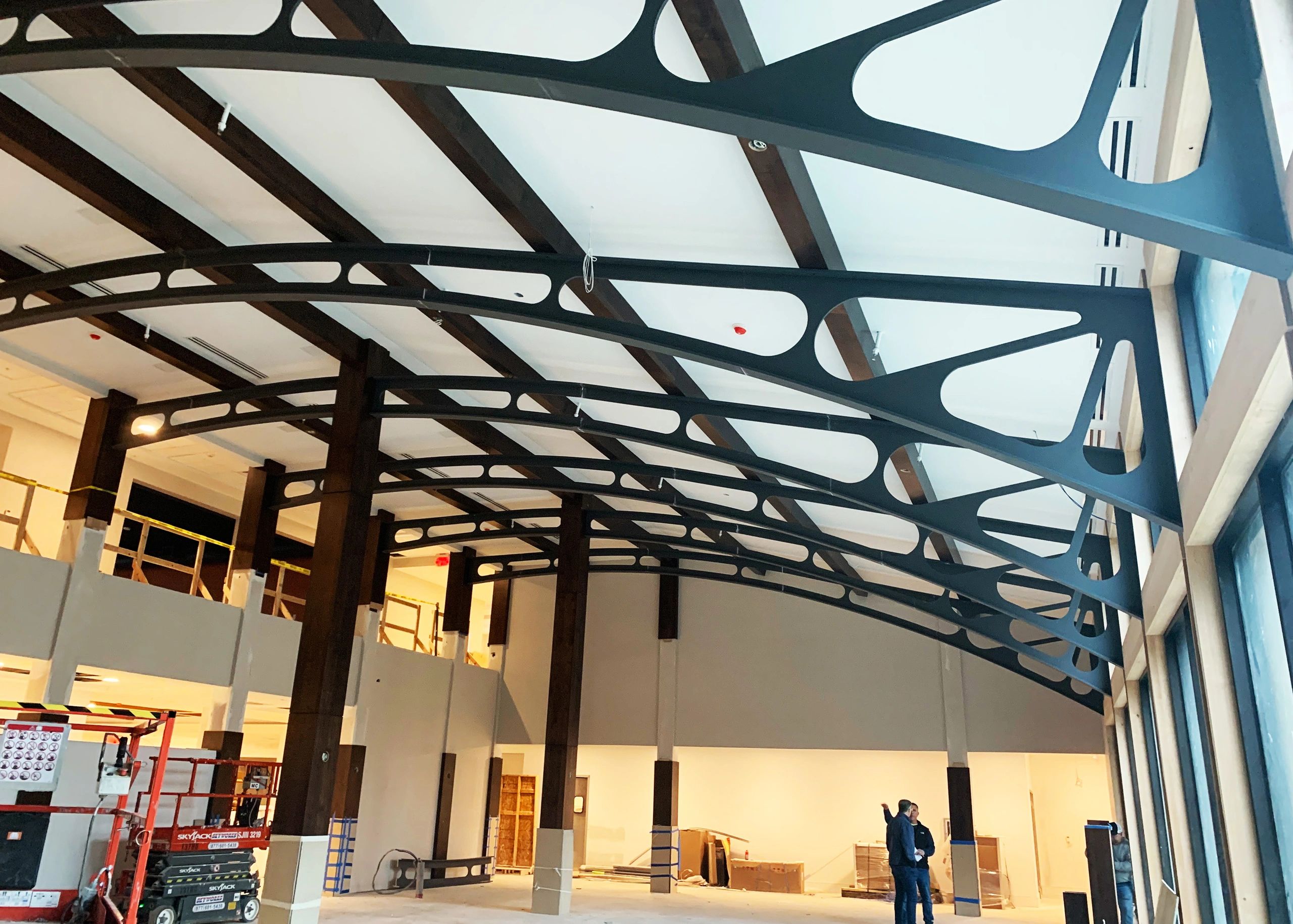 Event venue with dark steel trusses, Edison bulbs, and greenery