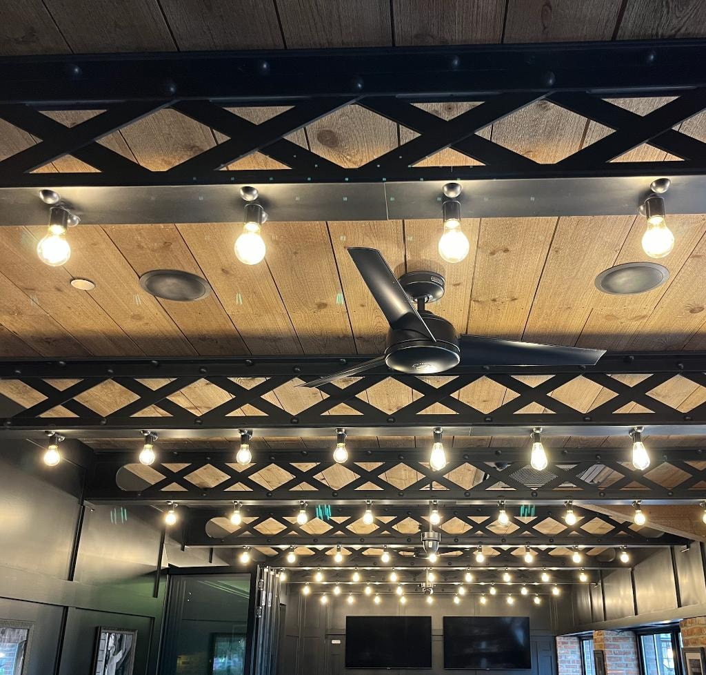 Black X-truss ceiling with integrated Edison bulb lighting and ceiling fan